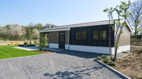 Modern Velthorst chalet in Kaatsheuvel, Netherlands, featuring a gravel driveway, lawn, and young trees.