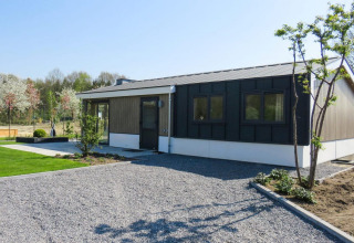Modern Velthorst chalet in Kaatsheuvel, Netherlands, featuring a gravel driveway, lawn, and young trees.