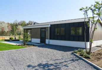 Modern chalet Velthorst te Kaatsheuvel in Nederland, met grindpad, gazon en jonge bomen.