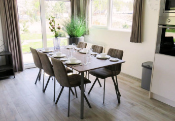 Zona pranzo luminosa e moderna al glamping Velthorst con tavolo apparecchiato per sei ospiti.