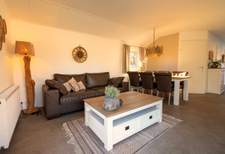 Wohnzimmer im Velthorst-Chalet in Kaatsheuvel, Niederlande mit Ledersofa, Esstisch und Dekoration.