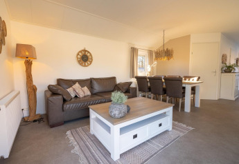 Woonkamer in Velthorst-chalet te Kaatsheuvel, Nederland, met lederen zetel en eettafel.