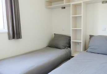 Vista interior de un alojamiento glamping Velthorst con dos camas individuales y ropa de cama gris.