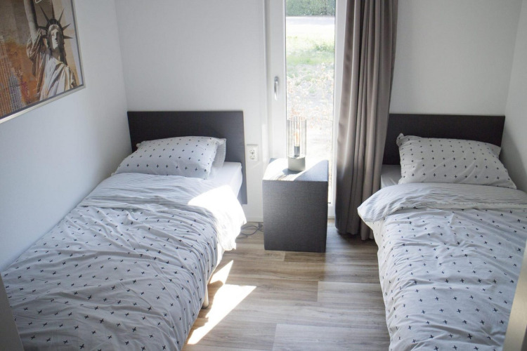 Dos camas individuales con ropa de cama a juego y una mesita de noche en un alojamiento glamping Velthorst.