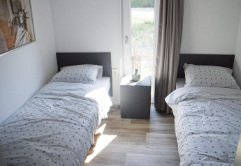 Dos camas individuales con ropa de cama a juego y una mesita de noche en un alojamiento glamping Velthorst.