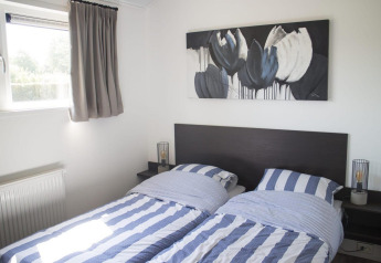 Dos camas individuales con sábanas a rayas azules y blancas en una habitación luminosa de glamping Velthorst.