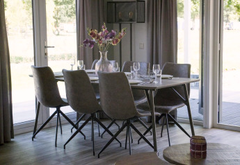 Sala da pranzo moderna con sei sedie e vaso di fiori nel chalet Velthorst a Kaatsheuvel, Paesi Bassi.
