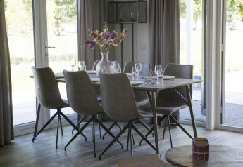 Moderne eetkamer met zes stoelen en een bloemenvaas in het Velthorst-chalet in Kaatsheuvel, Nederland.