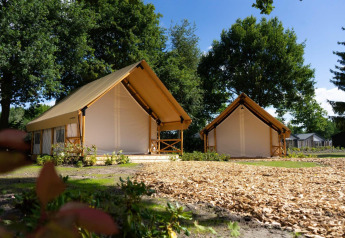 Zwei komfortable Safarizelte mit Holzveranda im Glamping-Bereich von Kaatsheuvel, Niederlande, bei Tageslicht.