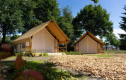 Twee comfortabele safaritenten met houten terras bij glamping Kaatsheuvel, Nederland, onder een heldere lucht.