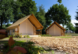 Due tende safari glamping con veranda in legno al campeggio di Kaatsheuvel, Paesi Bassi, in una giornata di sole.