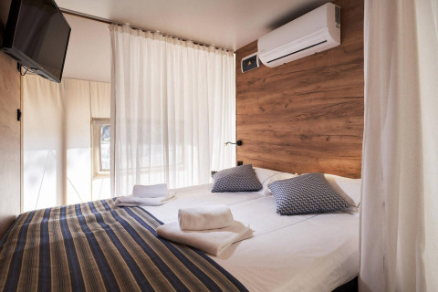 Vista interior de una tienda glamping de lujo en Kaatsheuvel, Países Bajos, con cama doble y decoración moderna.