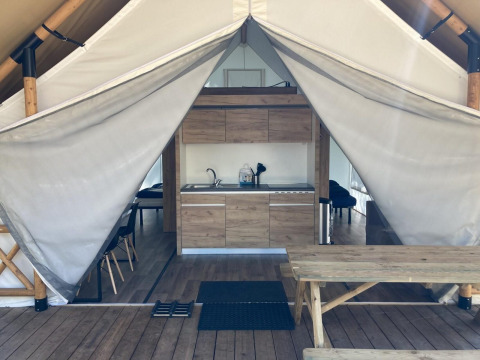 Vista interior de una tienda glamping con cocina y mesa de picnic en Kaatsheuvel, Países Bajos.