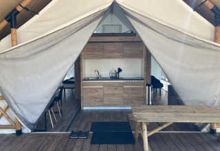 Vista interior de una tienda glamping con cocina y mesa de picnic en Kaatsheuvel, Países Bajos.
