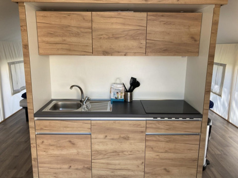 Moderne kitchenette in een glamping tent in Kaatsheuvel, Nederland, met houten kastjes en kookplaat.