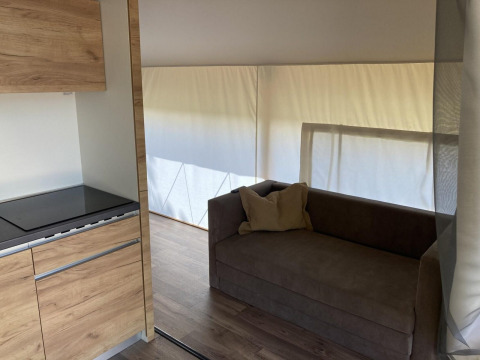 Innenbereich eines Glamping-Zeltes mit Sofa und Küche in Kaatsheuvel, Niederlande, sonnig beleuchtet.