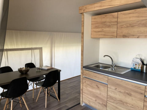 Interior de tienda glamping con cocina moderna y mesa de comedor con sillas negras en Kaatsheuvel, Países Bajos.