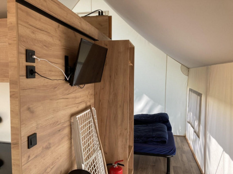 Innenraum eines Glamping-Zeltes in Kaatsheuvel, Niederlande mit Bett, Holzverkleidung und Fernseher.