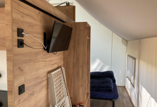 Indretning af et Glamping-telt i Kaatsheuvel, Holland med senge, træpaneler, tv og brandslukker.