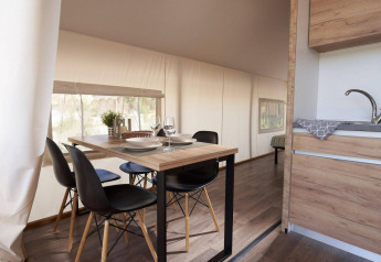 Zona pranzo moderna e angolo cottura in una tenda glamping a Kaatsheuvel, Paesi Bassi, con sedie nere.