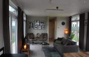 Sala moderna en Just Nature lodge en Kaatsheuvel, Países Bajos, con sofá, sillas y cuadros en la pared.