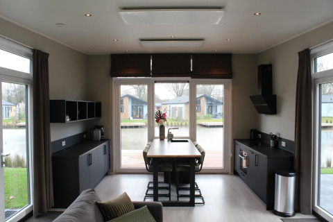 Modernes Interieur in der Lodge Just Nature in Kaatsheuvel, Niederlande, mit Ausblick auf einen See.