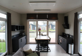 Lodge Just Nature i Kaatsheuvel, Holland, med moderne køkken, spiseplads og udsigt til vand og hytter.