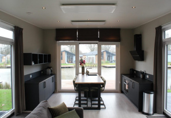 Lodge Just Nature i Kaatsheuvel, Holland, med moderne køkken, spiseplads og udsigt til vand og hytter.