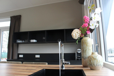 Cucina lodge moderna con piano in legno, lavello nero e fiori da Just Nature a Kaatsheuvel, Paesi Bassi.