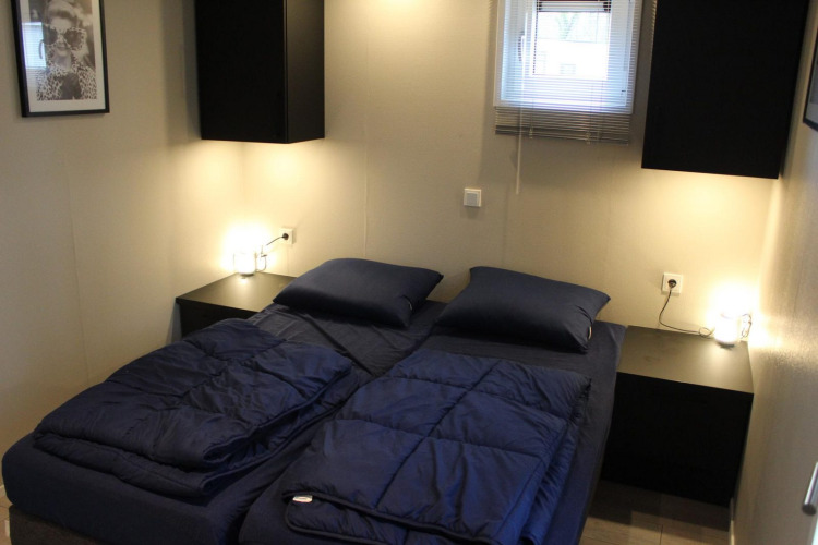 Dormitorio moderno en la cabaña Just Nature de Kaatsheuvel, Países Bajos, con camas dobles y sábanas azules.