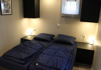 Dormitorio moderno en la cabaña Just Nature de Kaatsheuvel, Países Bajos, con camas dobles y sábanas azules.