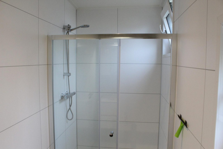 Douche moderne avec portes en verre et carrelage blanc au lodge Just Nature à Kaatsheuvel, Pays-Bas.