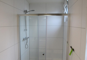 Moderne Dusche mit Glasschiebetüren und weißen Fliesen im Just Nature Lodge in Kaatsheuvel, Niederlande.