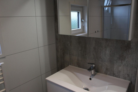 Salle de bain moderne avec lavabo, miroir et fenêtre au lodge Just Nature à Kaatsheuvel, Pays-Bas.