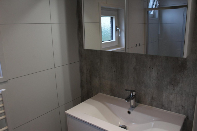 Moderno baño con lavabo, espejo y ventana en la lodge Just Nature en Kaatsheuvel, Países Bajos.