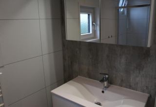 Modernes Badezimmer mit Waschbecken, Spiegel und Fenster in der Just Nature Lodge, Kaatsheuvel.