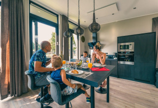 Famiglia fa colazione insieme in un moderno lodge di Just Nature a Kaatsheuvel, Paesi Bassi.