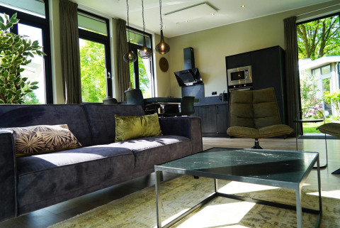 Soggiorno e cucina moderni in una tiny house di Just Nature a Kaatsheuvel, Paesi Bassi, con grandi finestre.