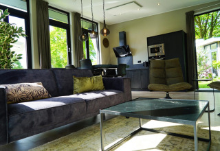 Soggiorno e cucina moderni in una tiny house di Just Nature a Kaatsheuvel, Paesi Bassi, con grandi finestre.