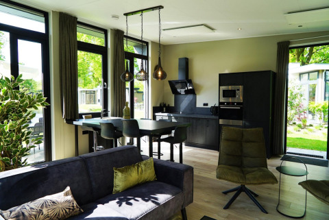 Moderne indretning i et lille hus med store vinduer, køkken, spisebord og sofa i Kaatsheuvel, Holland.