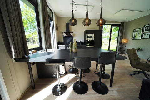 Cucina moderna e zona pranzo in una tiny house a Kaatsheuvel, Paesi Bassi, con grandi finestre e lampade a sospensione.