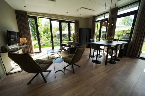 Salón moderno en la tiny house Just Nature en Kaatsheuvel, Países Bajos, con ventanales y vista al jardín.