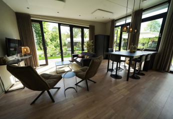 Salón moderno en la tiny house Just Nature en Kaatsheuvel, Países Bajos, con ventanales y vista al jardín.