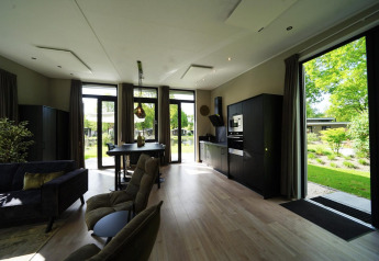 Modern tiny house-interieur te Kaatsheuvel in Nederland, met grote ramen en zicht op groene tuin.