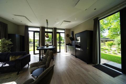 Modern tiny house-interieur te Kaatsheuvel in Nederland, met grote ramen en zicht op groene tuin.