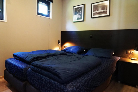 Chambre de la tiny house Just Nature à Kaatsheuvel, Pays-Bas, avec lit bleu et décor moderne, lampes douces.