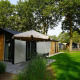 Udendørsbillede af Kids Adventure cottage med moderne facade, terrasse, parasol og grøn græsplæne.