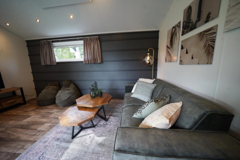Sala moderna del Kids Adventure cottage en Kaatsheuvel, Países Bajos, con sofá, mesas y arte en las paredes.