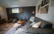 Sala moderna del Kids Adventure cottage en Kaatsheuvel, Países Bajos, con sofá, mesas y arte en las paredes.