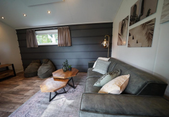 Sala moderna del Kids Adventure cottage en Kaatsheuvel, Países Bajos, con sofá, mesas y arte en las paredes.